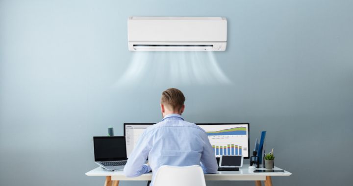 Man working in an office with an air conditioning unit on the wall