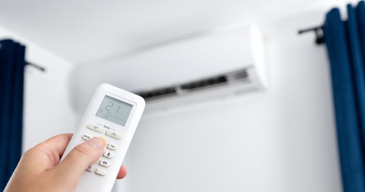 Person using a remote control to adjust the temperature of their wall mounted air conditioning unit