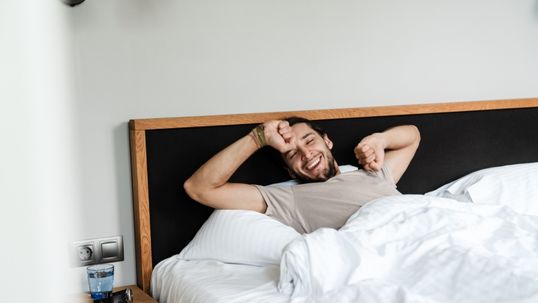 man waking up in bed happy