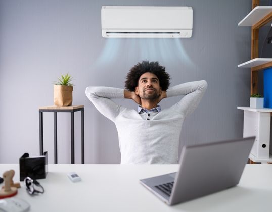 man enjoying wall mounted air conditioner while working from home
