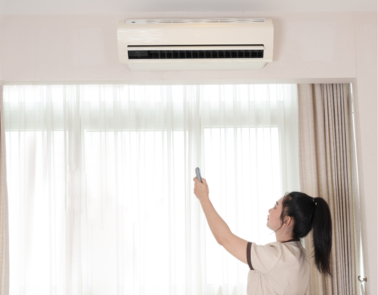woman operating wall mounted conditioner in bedroom
