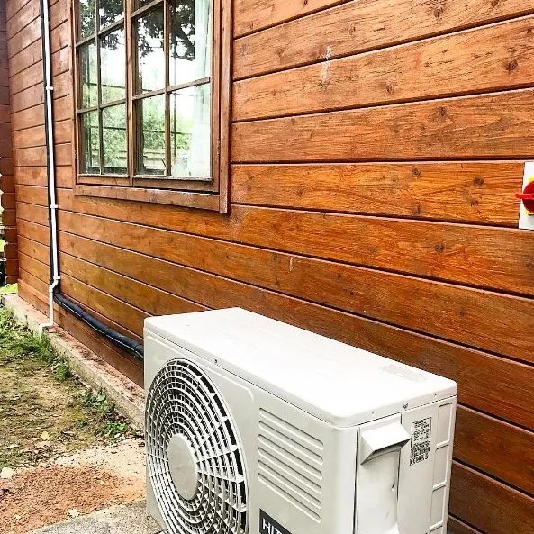 air conditioner outdoor unit outside wood panelled house